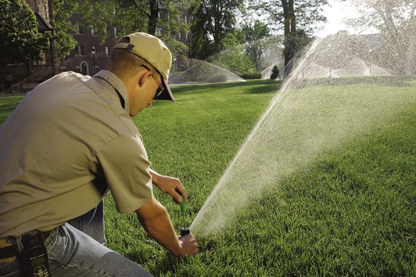 man adjusting the rotor on a park lawn sprinkler
